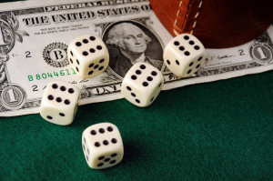 dices, leather cup and dollar bill   on green cloth